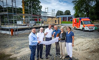 Tobias Mowitz (v.l., Firma Höfer), Stefan Laker, Dirk Fortmeier (Feuerwehr), Matthias Krieter (Höfer), Bettina Stöckel-Schepp und Ulrike Mößinger (ISB) schauen sich die Pläne für die neue Rettungswache (im Hintergrund) an. - Sarah Jonek Fotografie