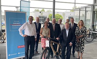 Claus Schleicher-Schnieder, Birgit Schnieder (erster und dritte v. l.) und Jochen Sudhölter (vierter v. r.) präsentieren Peter Eul (Mitte), Jens Prager (zweiter v.r.) und weiteren Gästen der Handwerkskammer sowie Tim Kähler (vorne rechts) die nachhaltigen Zweiräder. - Shannon-Lee Bendig