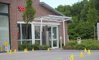 Mit Hütchen haben die Ermittler Spuren vor der Filiale der Sparkasse in Rödinghausen markiert. - Florian Weyand