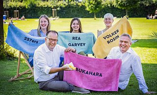 Martin Knabenreich, Geschäftsführer Bielefeld Marketing mit Freibad-Pommes, Marcus Lufen, Leiter Marketing und Innovationen der Stadtwerke Bielefeld auf der grünen Liegewiese, Eike Leoni Garnschröder, Karoline Jockheck und Katharina Schilberg, Projektleiterinnen, haben sich it ihren Handtüchern nach bester Hotel-Pool-Manier schon Plätze gesichert. - Sarah Jonek Fotografie
