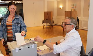 Charlene Bügler (36) hat ihr Kreuz gemacht und steckt ihren Wahlzettel unter den wachsamen Augen von Wahlhelfer Bruno Obens in die Wahlurne. - Claus Frickemeier