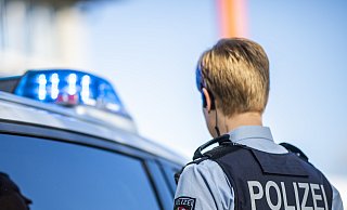 Eine Polizistin steht vor einem Streifenwagen, dessen Blaulicht leuchtet. Bei einem Einsatz in Gütersloh ist am Freitagabend eine Kommissarin schwer verletzt worden. - David Inderlied/dpa