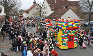 In Dreierreihen stehen die Besucher an den Straßenrändern. Vom Legoburg-Kinderprinzenwagen grüßen die Kinderprinzessinnen Laura II. und Finja I. - Johannes Büttner