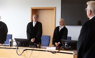 Martin Saal (2.v.l), Vorsitzender Richter, und Richard Uhle (r), Rechtsanwalt, stehen im Verhandlungssaal des Oberlandesgerichts Hamm. Das OLG beschäftigte sich mit einem Posting in den sozialen Medien während der Corona-Pandemie. - dpa/Dieter Menne