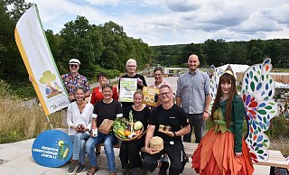 Jutta Sträter (Bioland-Hof Hartmann, vorn v. l.), Andreas Rode (Bäckerei Rode), Anna Lammert (Helle Bauer), Christian Valentin (Imkerei Familie Valentin) und LGS-Botschafterin Holli. Frederick Lüke (Umwelt-Bildungs-Initiative OWL, hinten v. l.), Claudia Koch (LGS-Geschäftsführerin), Günter Schumacher (BI Bördeland und Diemeltal), Martina Krog (Kreis Höxter) und Jan Sommer (LGS-Geschäftsführer). - Landesgartenschau Höxter