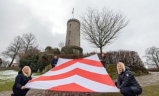 Stolze 3,50 mal 4,50 Meter ist die Sparrenburg-Flagge groß, die von Petra Löbbert (v.l.), Fabian Froböse, Julien Lienau und Deborah Becker gehalten wird. - Oliver Krato