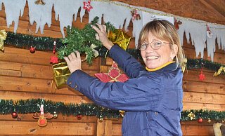Stefanie Ritzmann aus dem Vorstand des Vereins zur Förderung der Jugendarbeit Bünde bringt in den Hütten Tannengirlanden an, damit auch alles festlich geschmückt ist. In diesem Jahr findet die elfte Auflage von „Ein Weihnachtsbaum für Bünde“ statt. Foto: Peter Heidbrink - Peter Heidbrink