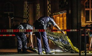 Polizeibeamte legen Folien über den Tatort. Sie versuchen damit die Spuren der Tat vor dem nächtlichen Regen zu schützen. - Paul Brinkmann
