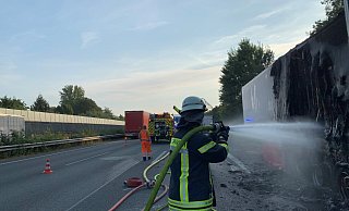 Ein Feuerwehrmann löscht nach dem Brand eines Lkw-Aufliegers noch einige Glutnester ab. Die Rauchentwicklung war nach dem Feuer weit über die Autobahn 2 hinaus zu sehen. Verletzt wurde niemand. - Daniel Hobein / Feuerwehr Bad Salzuflen