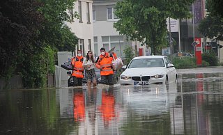 Anfang Juni hatten auch Bünde und Enger mit Wassermassen zu kämpfen. Feuerwehrmänner begleiten eine Frau durch das Hochwasser an der Engerstraße in Bünde. - Florian Weyand
