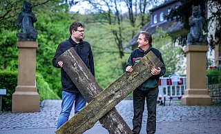 Benjamin Ibler (Abschnittsleiter Tierpark, l.) und Herbert Linnemann (Leiter Forsten und Tierpark) am Eingang mit Balken des Holzzaunes, der abgebaut wird. Sie freuen sich über den neuen festen Zaun, der jetzt kommt, „weil er zum Wohl der Tiere ist“. - Sarah Jonek Fotografie