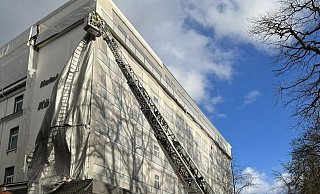 Mittels Drehleiter entfernte die Feuerwehr die herabstürzende Plane von der Fassade des Königshofes. - Feuerwehr Bad Oeynhausen