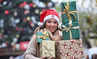 NW-Volontärin Sevim Hangül steht vor dem großen Weihnachtsbaum auf dem Alten Markt und macht Werbung für die beliebte Aktion. - Frank-Michael Kiel-Steinkamp