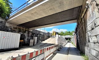 Parallel zu den Stützmauern der Brücke ist eine Wand aus großen Quadern mit Noppen drauf entstanden. Eine Seite ist verfüllt und gibt der Mauer Halt. - Simone Flörke