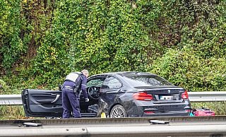 Ein Polizist inspiziert den Unfall-BMW. - Paul Brinkmann