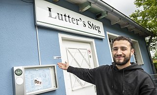 Neue Gastro Luttersteg: Betreiber Delschad Nemat zeigt seine kleine Speisekarte. Im Hintergrund die Ausgabestelle für Eis und Drinks "to go". - © Jörg Dieckmann - www. dieckmann-fotodesign.de