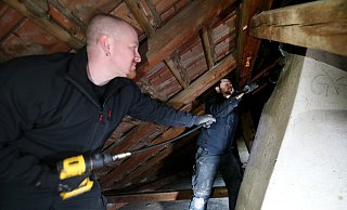 Sören Meyer (links) und sein Mitarbeiter Nick Schellenberg kommen dem Dohlennest im Kamin mit einer Spindel bei, die von einem Akkuschrauber angetrieben wird. Ein Großteil des Nistmaterials fällt dabei durch den Schacht in den Keller, wo er später eingesammelt wird. Hier kam zwischen 15 und 20 Liter zusammen. - Gerald Dunkel