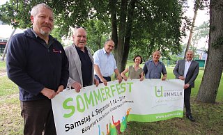 Für das Sommerfest werben mit einem Banner Daniel Ernst von den Johannitern (v. l., alle geimpft), Pastor Uwe Winkler, Holger Stritzke, Ricarda Robrecht und Pfarrer Reinhard Bogdan von der Evangelischen Kirchengemeinde sowie Hubert Erichlandwehr. - Sabine Kubendorff