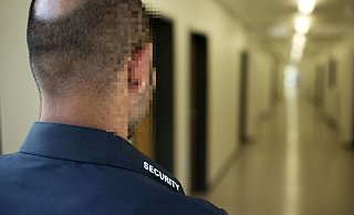 Ein Mitarbeiter einer Sicherheitsfirma (Symbolfoto) auf dem Gang einer zu bewachenden Einrichtung. - picture alliance / photothek