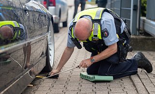 Ein Polizist kontrolliert die Bodenfreiheit eines vermeintlich zu tiefen 7er-BMW. Sie ist ausreichend: Der BMW darf weiterfahren. - Oliver Krato