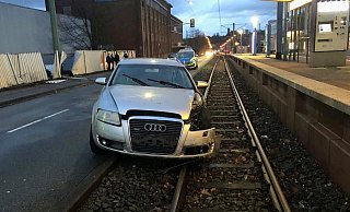 Der Audi blieb auf den Schienen der Linie 1 liegen. Zuvor war der Wagen in einen Zaun auf der anderen Seite (l.) geprallt. - Polizei