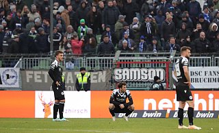 Die Spieler von Arminia Bielefeld stehen nach dem späten 2:2-Ausgleich beim VfB Lübeck ernüchtert auf dem Platz. - IMAGO/Nordphoto