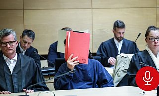 Einer der Angeklagten versteckt sein Gesicht hinter einem roten Aktendeckel. Er wird von den Strafverteidigern Detlev Binder (l.) und Susanne Renner vertreten. Hinter ihnen sitzt der zweite Angeklagte, der ebenfalls unerkannt bleiben will. - Sarah Jonek
