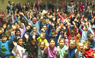 Inmitten von Schülerinnen und Schülern der Grundschule Enger-Westerenger sitzen Rüdiger Brameyer und neben ihm Angelika Riese. Beide wurden jetzt in den Ruhestand verabschiedet. Und die Feier dazu rührte die Neurentner sehr. - Andreas Sundermeier