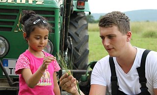 Landwirt Timo zeigt Lily die Grannen an der Getreideähre. Beim Bauernhof-Erlebnistag wird ein vielfältiges Programm mit Aktionen, Informationen und Köstlichem für die Großen unddie Kleinen geboten. - WLV