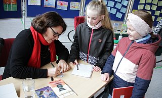 Kinderbuchautorin Julia Boehme schreibt nach der Lesung in der Turnhalle für Lina und Xenia Autogramme. - Dieter Scholz
