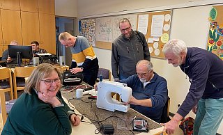 Das Repair-Café in Schloß Neuhaus im Einsatz: Marie-Luise Tigges (v.l., freut sich über die Reparatur ihrer Nähmaschine), Dietmar Jakobsmeyer, Pfarrer Oliver Peters (stellt die Räumlichkeiten zur Verfügung), Helmut Kölling und Martin Beierle (Quartiersinitiative). - Quartiersinitiative Schloß Neuhaus