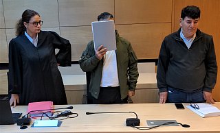 Der Angeklagte verdeckt mit einer Mappe sein Gesicht. Neben ihm sind seine Anwältin Dinah Busse sowie der Dolmetscher des 41-Jährigen. Foto: - Nils Middelhauve