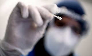 Ein Arzt hält ein Teststäbchen für einen Corona-Test in der Hand. Aktuell pendeln sich die Inzidenzen auf einem hohen Niveau ein, die kostenlosen Bürgertests gibt es aber nur bis Ende Juni. - Britta Pedersen