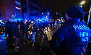 Selbstbewusst diskutieren diese Spaziergänger, dass die Polizeikette vor ihnen am Niederwall nicht halten würde, wenn sie alle drauf zugingen. Hier tun sie es nicht und drehen wieder ab. - Foto: Andreas Zobe/NW