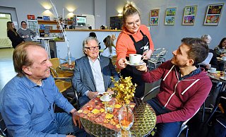 Rimante Krapiene serviert Gesangslehrer Andreas Post von der Musik- und Kunstschule einen Cappuccino. Johannes Strzyzewski (l.) und Franz Schaible freuen sich, dass die Zwangspause im Café endlich vorbei ist. - Barbara Franke