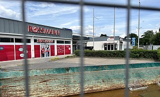 Der Baucontainer ist bereits halbvoll mit Regenwasser, im Hintergrund sind die drei Ladenlokale zu sehen, die saniert werden. Ein wirklicher Fortschritt ist auch nach Monaten nicht zu erkennen. - Nicole Sielermann