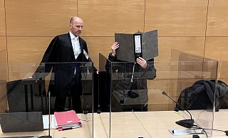 Rechtsanwalt Peter Rostek mit dem angeklagten 33-jährigen Bielefelder. Er verdeckt sein Gesicht vor Fotografen und TV-Teams mit einem Aktenordner - Jens Reichenbach