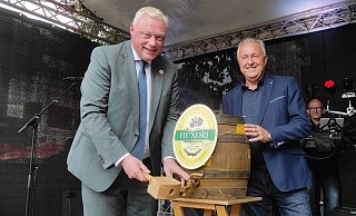 Bürgermeister Daniel Hartmann (l.) braucht bei seiner Huxori-Markt-Premiere drei Schläge, bis das Bier fließt. Jürgen Knabe (Werbegemeinschaft) unterstützt. - Svenja Ludwig