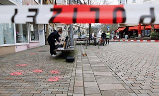 Eine Polizeibeamtin der Kriminaltechnik steht am abgesperrten Tatort. Für eine Laseranalyse des Tatortes hat sie die Fundorte der 16 Patronenhülsen rot markiert. - Friso Gentsch/dpa