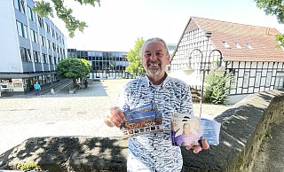 Am Donnerstagabend startet die Bünder Sommerkultur wieder auf dem Rathausplatz im Hintergrund. Ansonsten hält Dirk Kaiser das prall gefüllte Veranstaltungsprogramm für Universum und Stadtgarten bis Februar 2025 in der Hand. - Natalie Gottwald