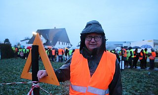 Jens Köster, Vorsitzende Widuland-Initiative, auf dem Acker in Elverdissen, wo eine mögliche ICE-Neubautrasse herführen könnte. Im Hintergrund Mitstreiter und Demonstranten. - Susanne Blersch