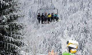 Skifahrer fahren in Winterberg bei winterlichem Wetter in einem Sessellift an einer Schneekanone vorbei. - Bernd Thissen