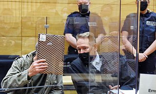 Mit einem Pappdeckel verdeckt betritt Ercan K. den Gerichtssaal, neben ihm sein Strafverteidiger Carsten Ernst. - Barbara Franke