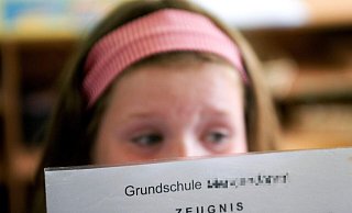 Eine Schülerin betrachtet in einer Grundschule ihr Zeugnis. Es scheint böse Überraschungen zu geben. - Michael Löwa/dpa