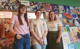 Startklar für den Manga Day: die Azubis Julia Rathert und Lara Pietsch mit Veranstaltungskauffrau Natalia Baron (v.l.) vor einen bunten Manga-Wand in der Bibliothek am Neumarkt. - Heike Krüger