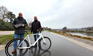 Auf dem wieder geöffneten Weserradweg: LGS-Geschäftsführer Jan Sommer (l.) überreicht das moderne E-Bike an Gewinner Michael Schulte. - LGS Höxter/Madita Schellenberg