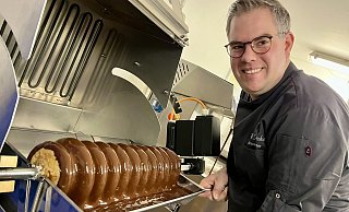 Die Baumkuchenmaschine war eine große Anschaffung für den Chocolatier. Patrick Dreker produziert damit Variationen in diversen Schokoüberzügen und Größen. Viele Kunden kennen die Leckerei nur noch aus der industriellen Produktion. Die Herstellung ist aufwendig, weil bis zu 20 Teigschichten zügig aufgebracht werden müssen. - Jens Reddeker
