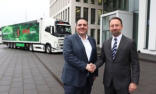 Dirk Mutlak (l.) und Christoph Fitz schütteln sich die Hände. Vor der Hauptverwaltung steht eine der beiden neuen vollelektrischen Sattelzugmaschinen, die die Tönnies-Logistiktochter Tevex von Volvo gekauft hat. - Marion Pokorra-Brockschmidt