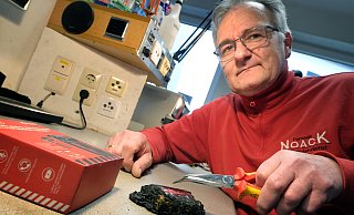 Die verkohlte Powerbank hat beinahe die komplette Wohnung seines Sohnes in Brand gesteckt. Ihre Überreste fasst der Gütersloher Radio- und Fernsehtechniker-Meister Frank Noack nur noch mit der Zange an. - Andreas Frücht