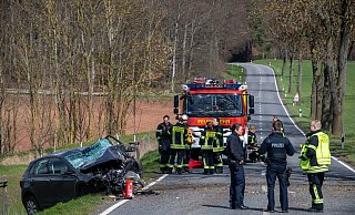 Polizistinnen und Polizisten und Feuerwehrleute stehen neben dem verunfallten Wagen. - dpa